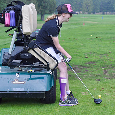 athlete hitting golf ball from solo rider adaptive golf cart