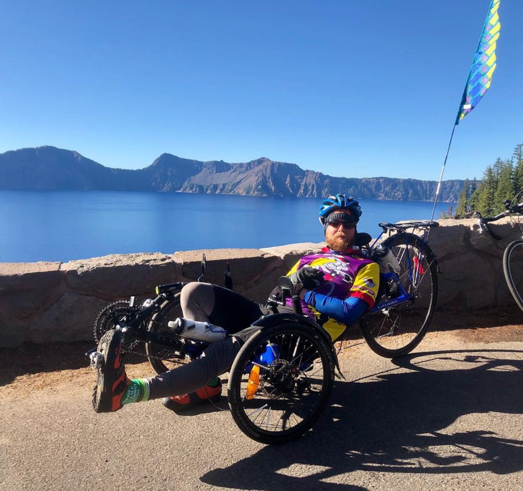 cyclist on recumbent bike in front of crater lake