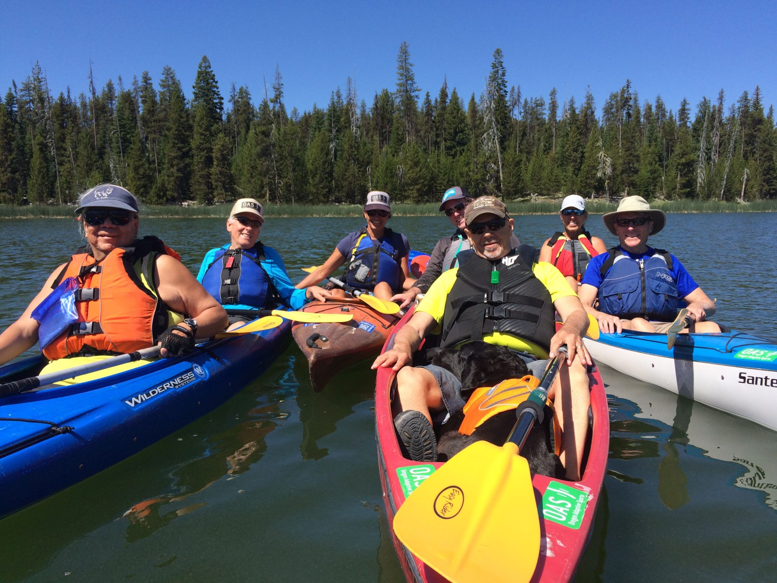 group of folks in kayaks on sparks lake grouped together holding onto each other's boats and smiling for photo