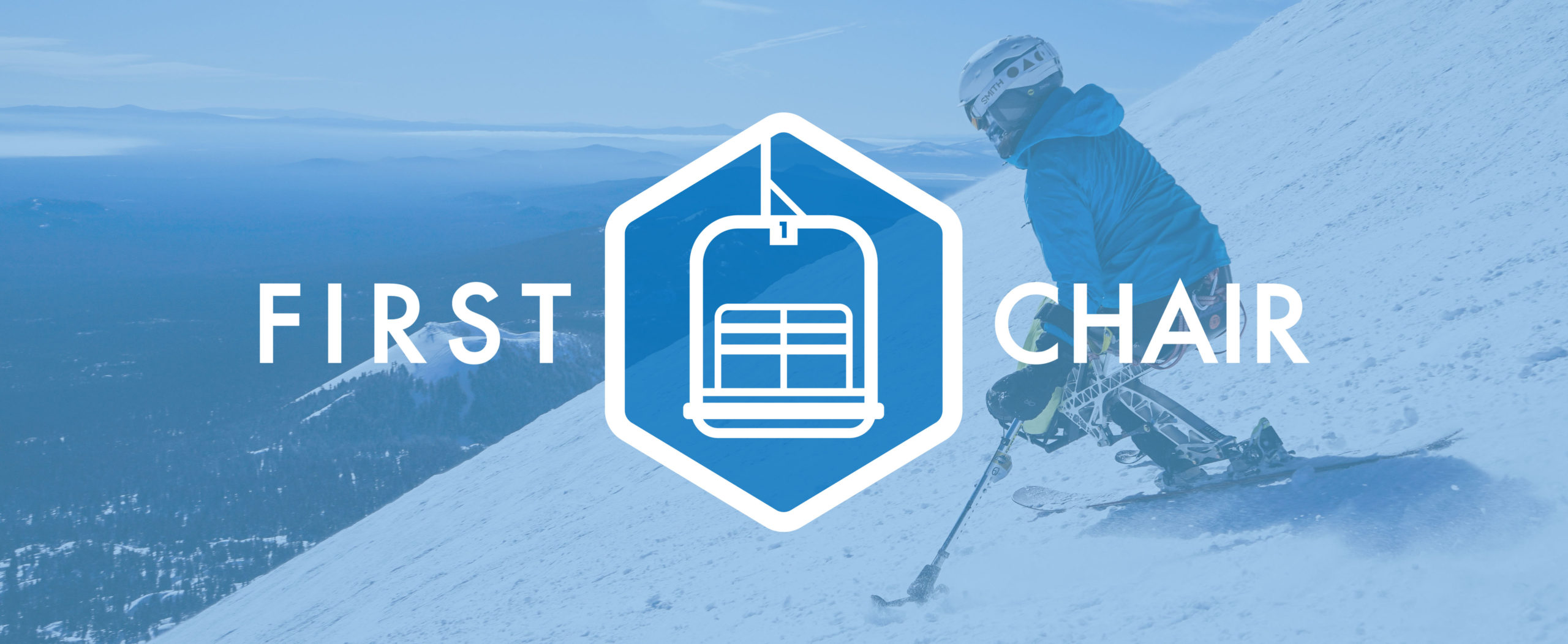 First Chair Logo placed over a photo of a ski skier overlooking their route down the mountain, there is a blue tone over the image. 