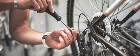 Close up shot on male hands inside bicycle store while repairing the gearshift on rear wheel of a mountain bike.