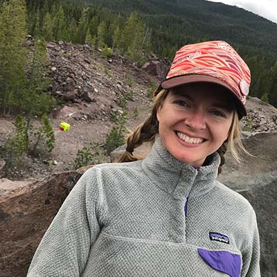 Cara smiling and posing outside wearing a trucker hat and a Patagonia fleece