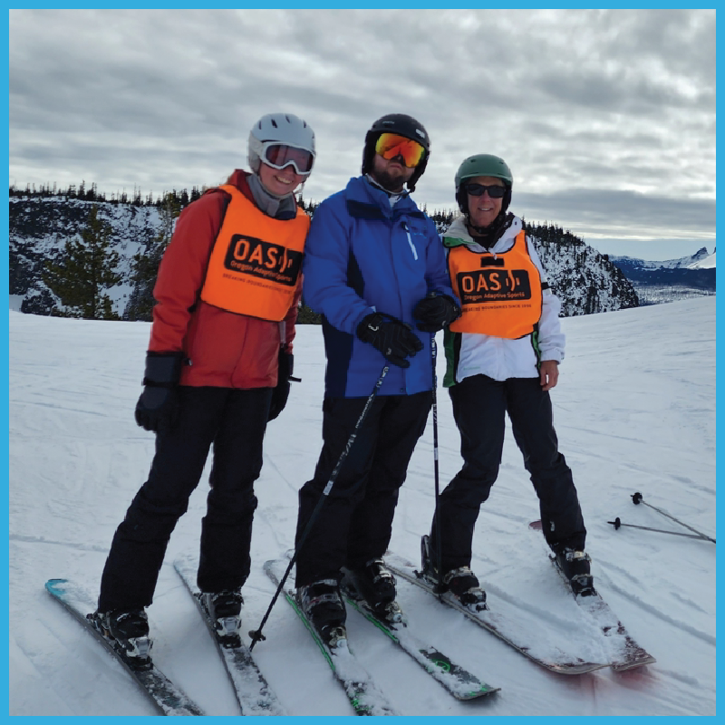 Two OAS Guides standing beside an athlete at the start of a ski trail. All are on two-track skies.