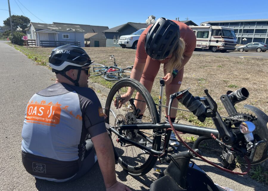 OAS Staff supporting an adaptive athlete by pumping more air into their tire.