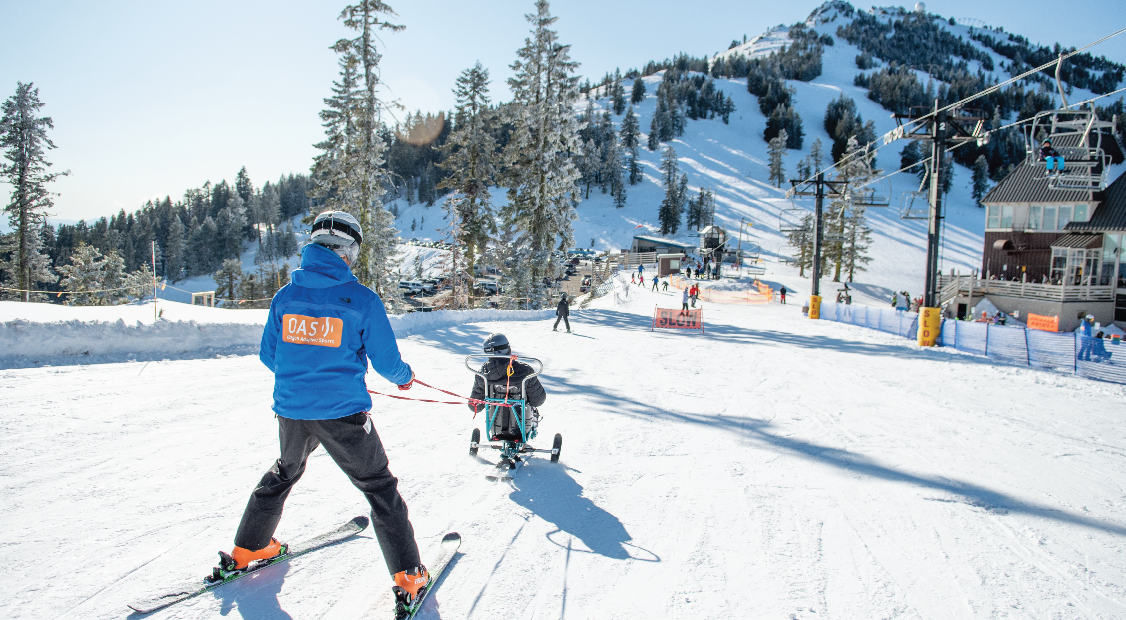 An instructor works with a sit skier on the slope in use of equipment at Mt. Ashland