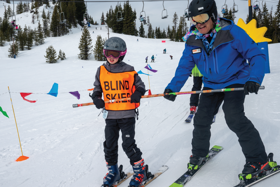 Young athlete who is visually impaired skis down the hill with an OAS instructor