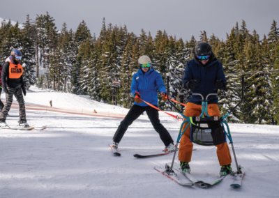 OAS instructor with an adaptive athlete participating in Heroes. They are using a slide unique with meets the needs of stand up skiers to offer balance.