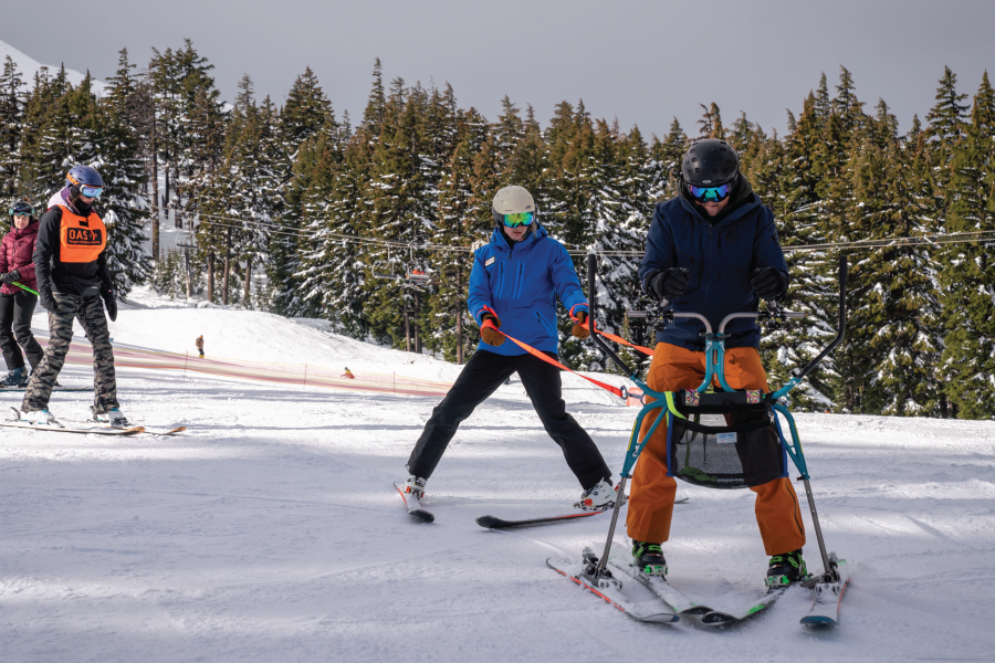 OAS instructor with an adaptive athlete participating in Heroes. They are using a slide unique with meets the needs of stand up skiers to offer balance.