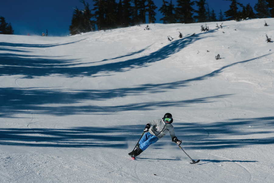 3-track skier sending it down the snowy slope. wearing blue snowpants and a white jacket