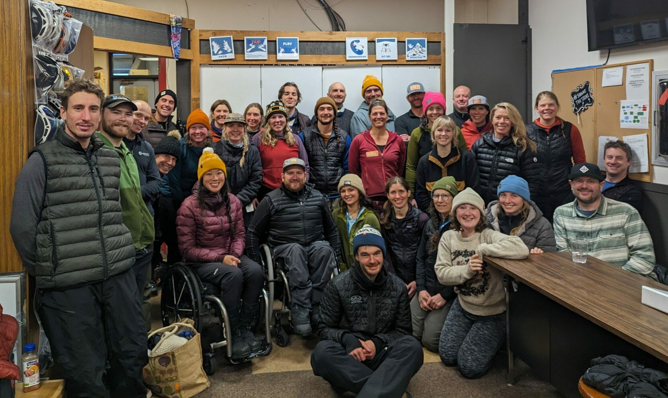 The OAS winter instructor staff packed together for a group photo inside of the OAS Mt Bachelor office. Many are wearing beanies and puffy jackets after a day of training out on the snow.