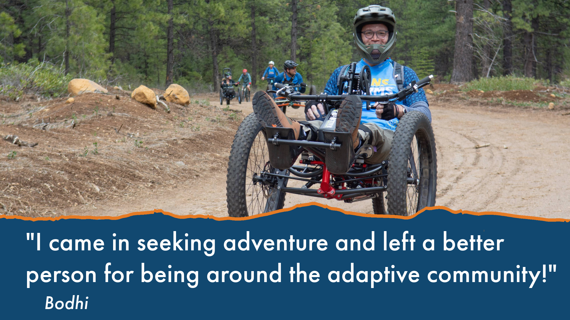 text: I came in seeking adventure and left a better person for being around the adaptive community! image: Bodhi with a full-face helmet smiles and stops for the camera on the double track with a few other participants trailing behind him. 