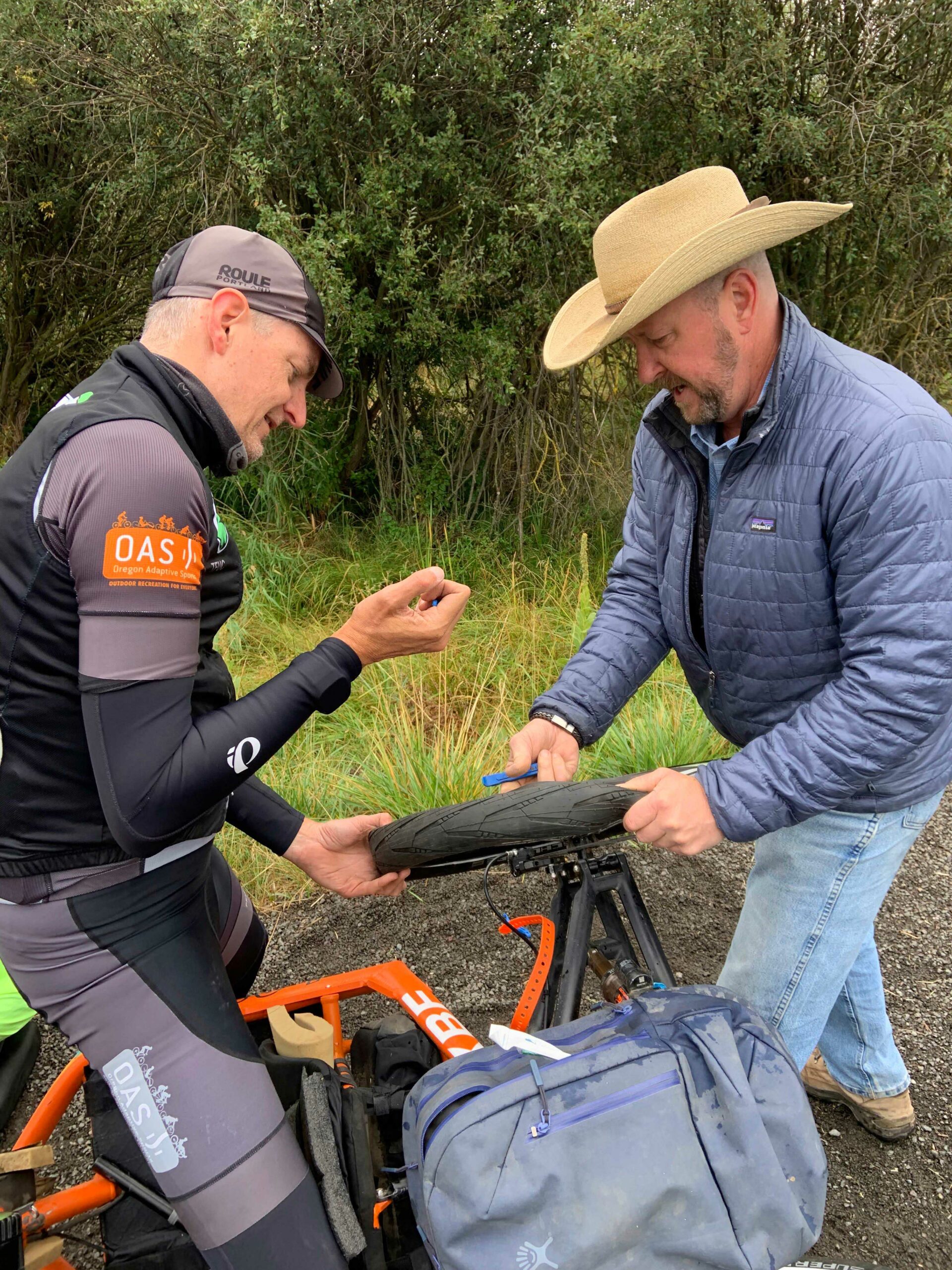 Two OAS volunteers pair up to repair a handcycle with a punctured tire from a tack