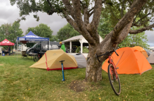 propped against a tree is a tandem cycle with some tents pitched on the ground