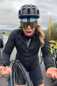 OAS staff member makes an "Oh No!" face with arms open and a bike tire between her hands showing a tack in the tire