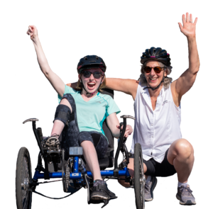 OAS volunteer kneels down beside an athlete in a recumbent bike, both have an arm up with smiles to cheer