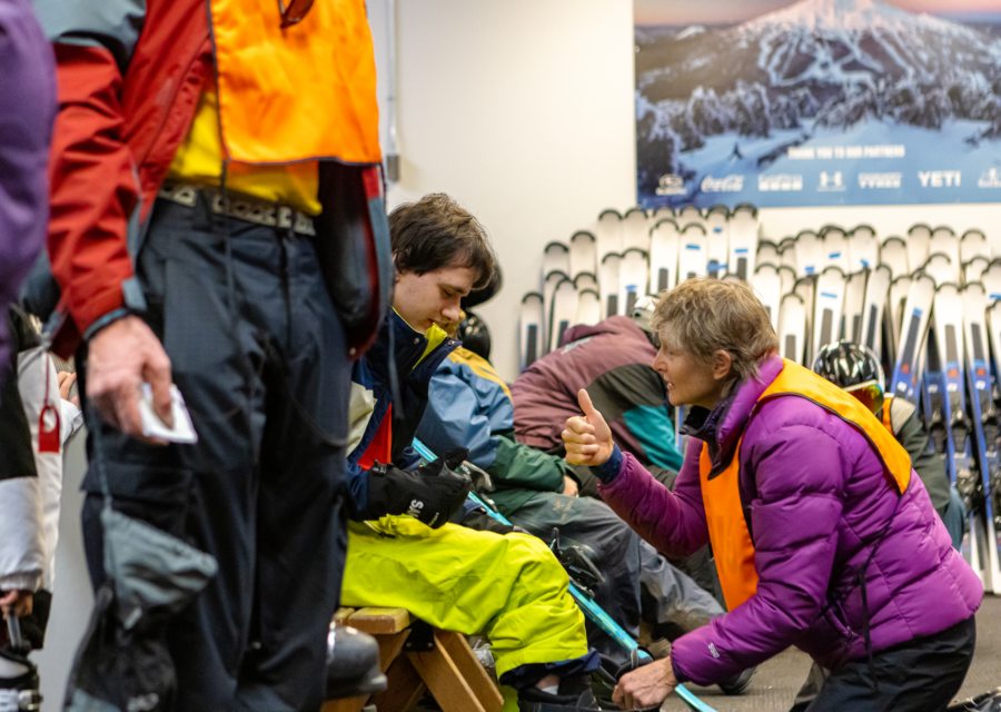 An OAS volunteer gives the thumbs up to an athlete while adjusting their boot.