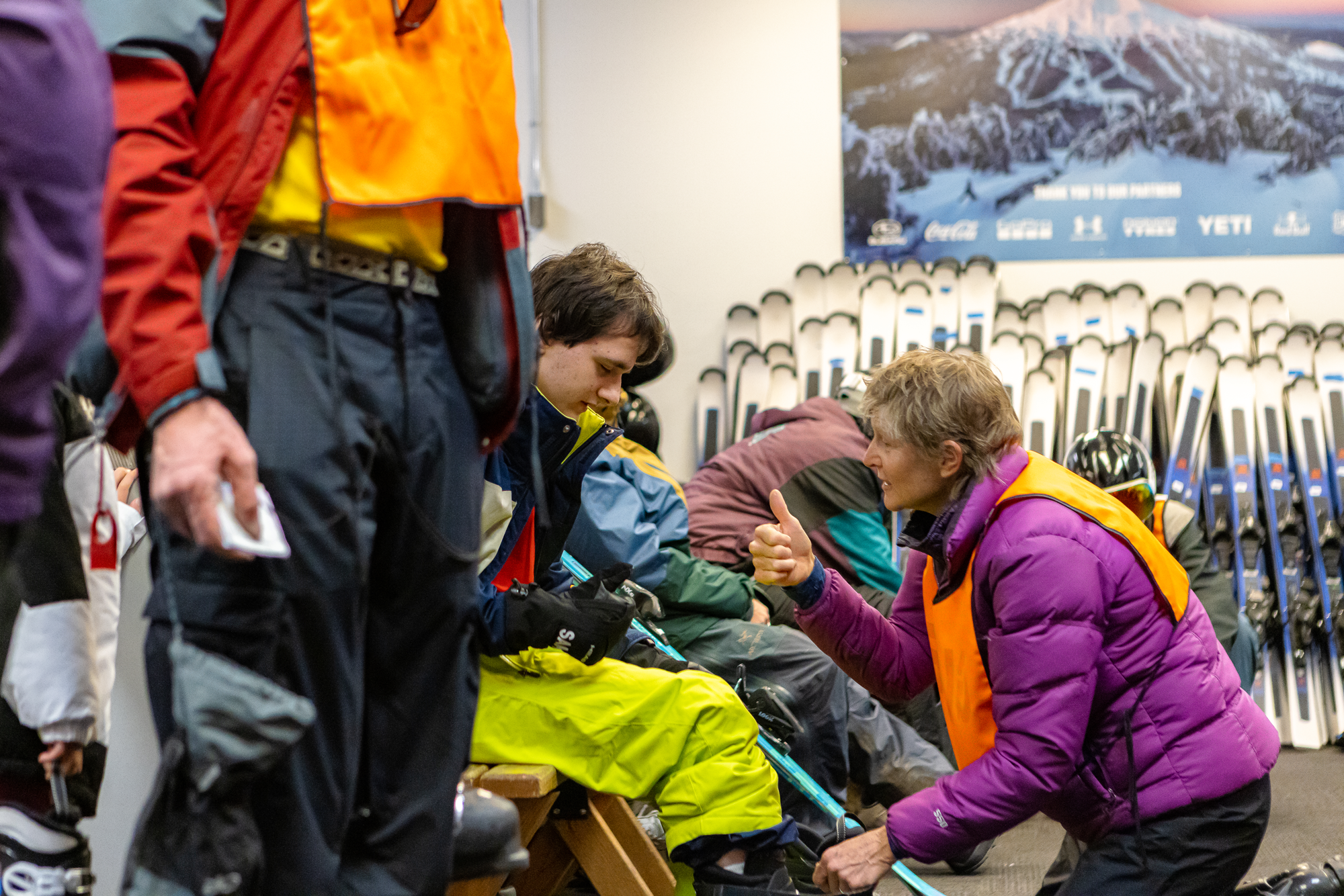 An OAS volunteer gives the thumbs up to an athlete while adjusting their boot.