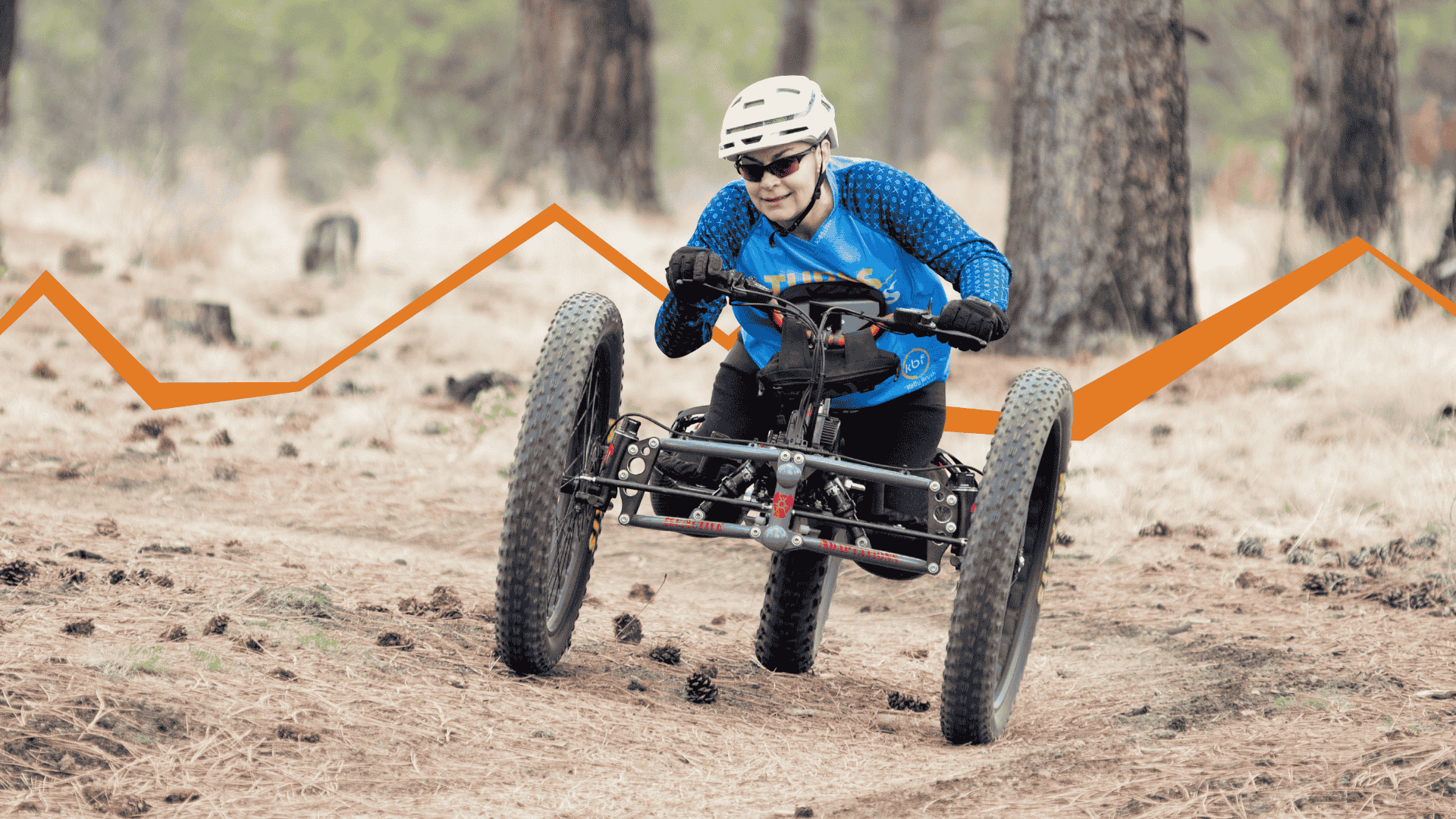 Molly on an adaptive mountain bike with hand cycle capacity. the orange mountain