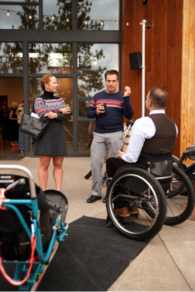 a couple wearing matching knit sweaters chat with an O-A-S ambassador near the equipment display.