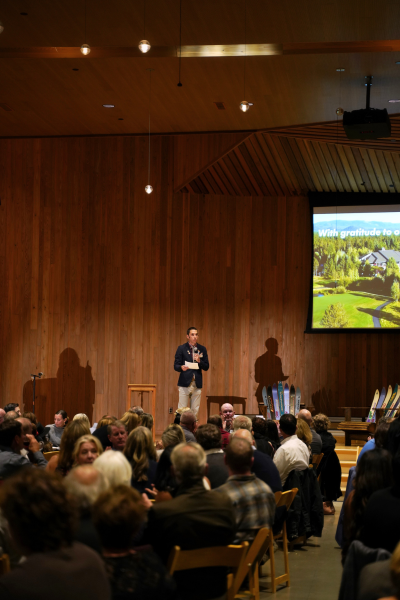 a man wearing a sportcoat and khakis speaks on stage.