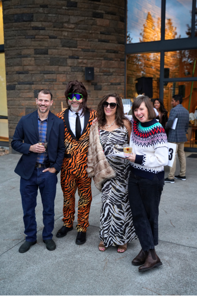 Four people pose for a photo. They are all dressed up, and the two in the middle wear full tiger and zebra striped outfits.