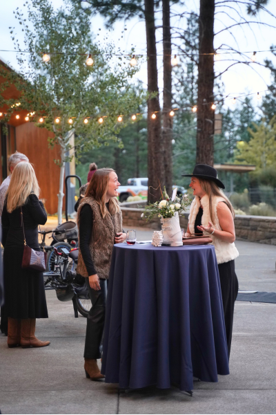two women chat across a cocktail table on the patio.