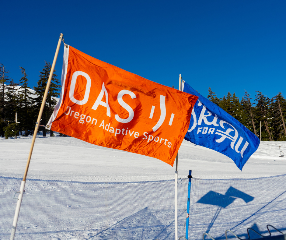 the orange O-A-S flag flies in the wind next to the blue Ski For All flag.