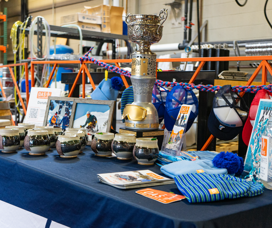 the ski for all trophy: a tall silver and gold trophy with gold goggles on it, sits on a table of O-A-S swag at the after party.