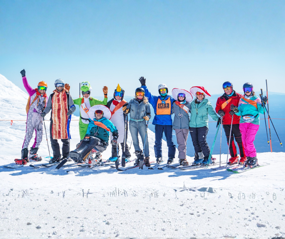a group of people, all wearing colorful mario themed costumes pose at the top of a lift for a photo.