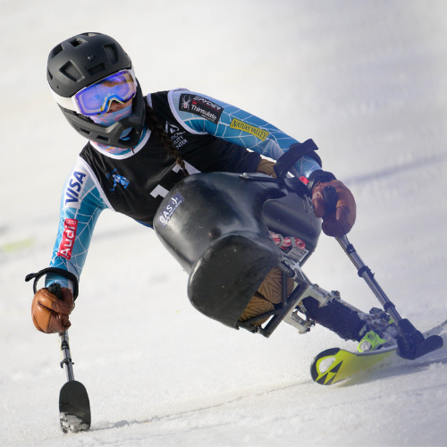 Anna carves toward the right of screen, using a monoski in a slalom race
