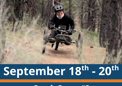 September 18th to 20th. Crank Camp number 3. aMTB Skills Camp. A person wearing a helmet rides a three-wheeled adaptive mountain bike along a narrow dirt trail through a forest, moving between tall trees with dry grass in the foreground.