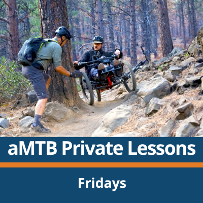 aMTB Private Lessons. Fridays. A person rides a three-wheeled adaptive mountain bike down a rocky forest trail while another person walks alongside and reaches out to assist, with trees, rocks, and dirt trail surrounding them.