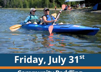 Friday, July 31st. Community Paddling. Paddle and Play. Two people paddle a blue tandem kayak across a lake, each holding a double-bladed paddle, with a forested shoreline