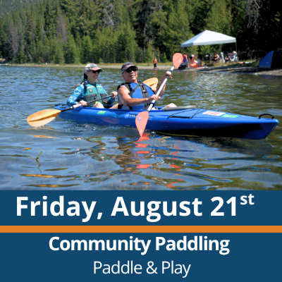 Friday, August 21st. Community Paddling. Paddle and Play. Two people paddle a blue tandem kayak across a lake, each holding a double-bladed paddle, with a forested shoreline