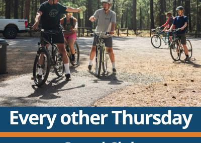 Every other Thursday. Gravel Club. Location rotates. A small group of people stand and ride bikes on a gravel area in a forest