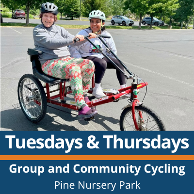 Tuesdays and Thursdays. Group and Community Cycling. Pine Nursery Park. Two people wearing helmets ride a red side-by-side adaptive cycle on a paved parking lot, both smiling and holding the handlebars, with parked cars and trees in the background.