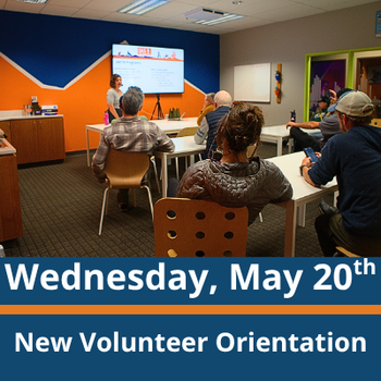 Classroom scene; a group of adults sit at tables facing a presenter standing near a screen at the front of the room; the presenter gestures toward the screen while speaking; text at the bottom reads “Wednesday, May 20th” and “New Volunteer Orientation.”