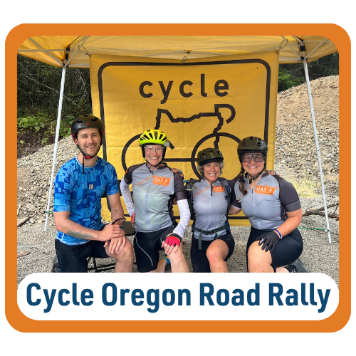 Graphic with text reading “Cycle Oregon Road Rally.” Four smiling cyclists wearing helmets pose together beneath a yellow tent with a sign reading “cycle Oregon.” Three wear gray O-A-S cycling jerseys while one wears a blue cycling jersey. A gravel road and rocky hillside are visible behind them.