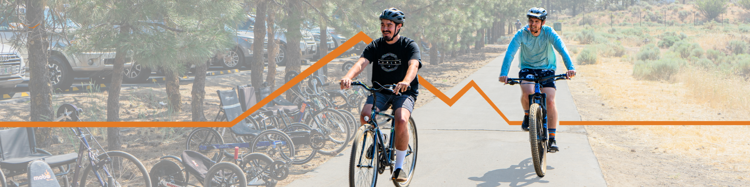 Two people ride bicycles on a paved path. Several adaptive cycles are parked beside the trail while an orange trail-shaped graphic runs across the image.